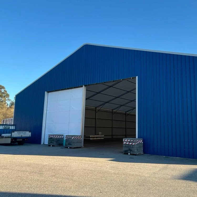 Nave agrícola desmontable azul con estructura metálica y cerramientos laterales para almacenamiento de grano o maquinaria