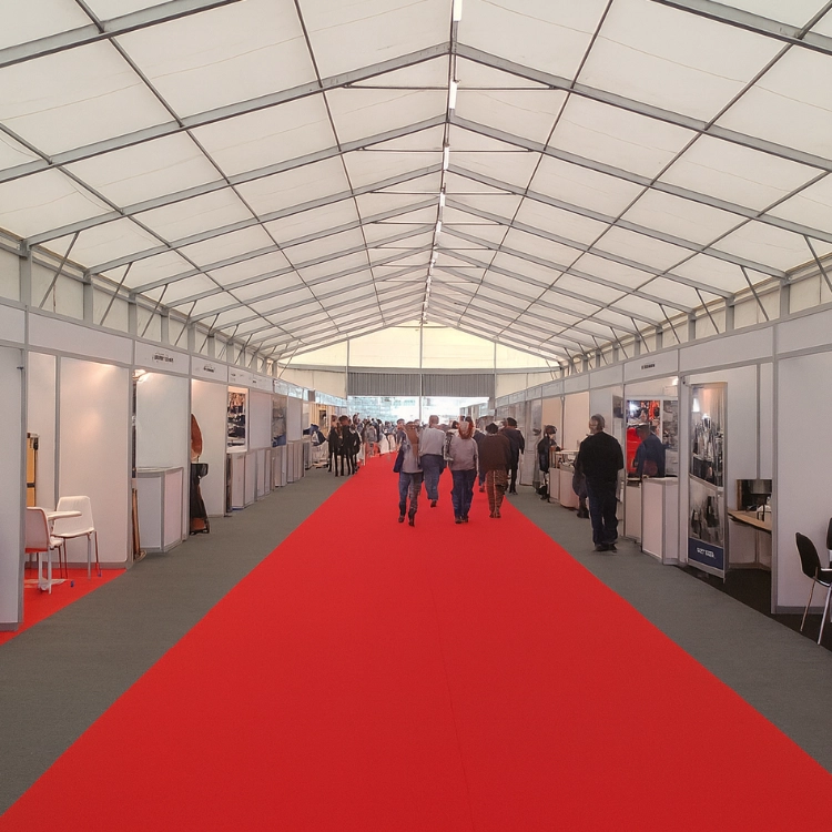 Interior de nave ferial desmontable con stands expositivos y moqueta roja para eventos corporativos o congresos